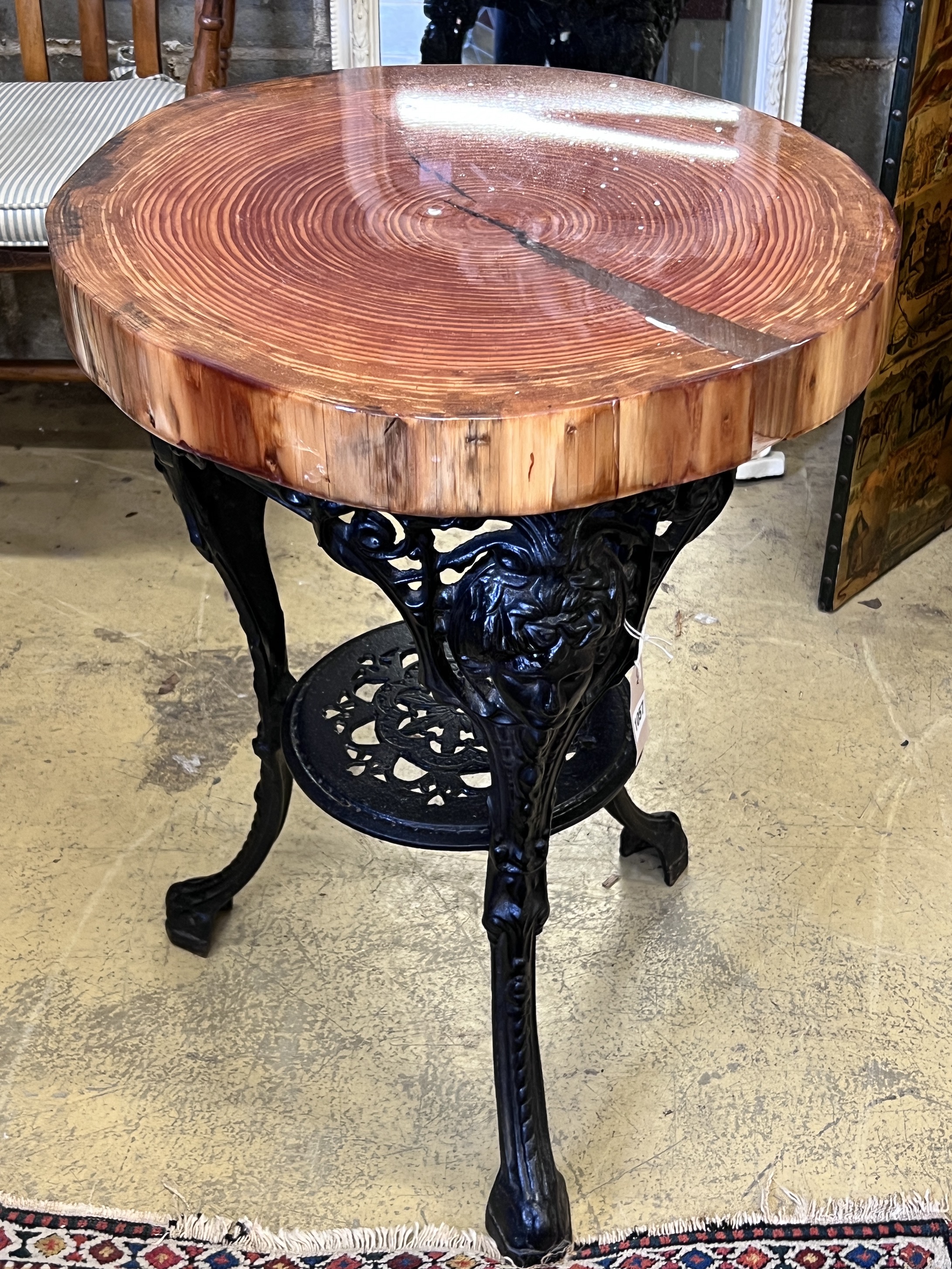 A resin encased cedar wood occasional table with cast iron underframe, diameter 53cm